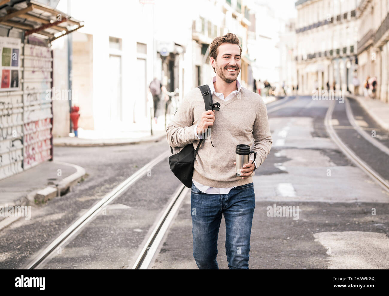 Sorridente giovane con zaino e tazza da caffè in città il go, Lisbona, Portogallo Foto Stock