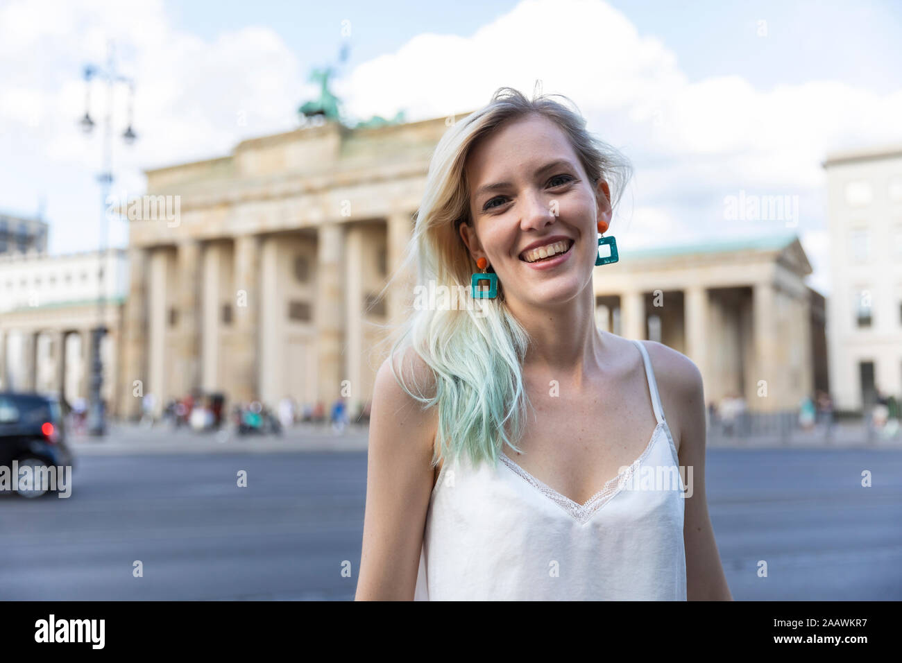 Ritratto di sorridente giovane donna di fronte Brandenburger Tor, Berlino, Germania Foto Stock