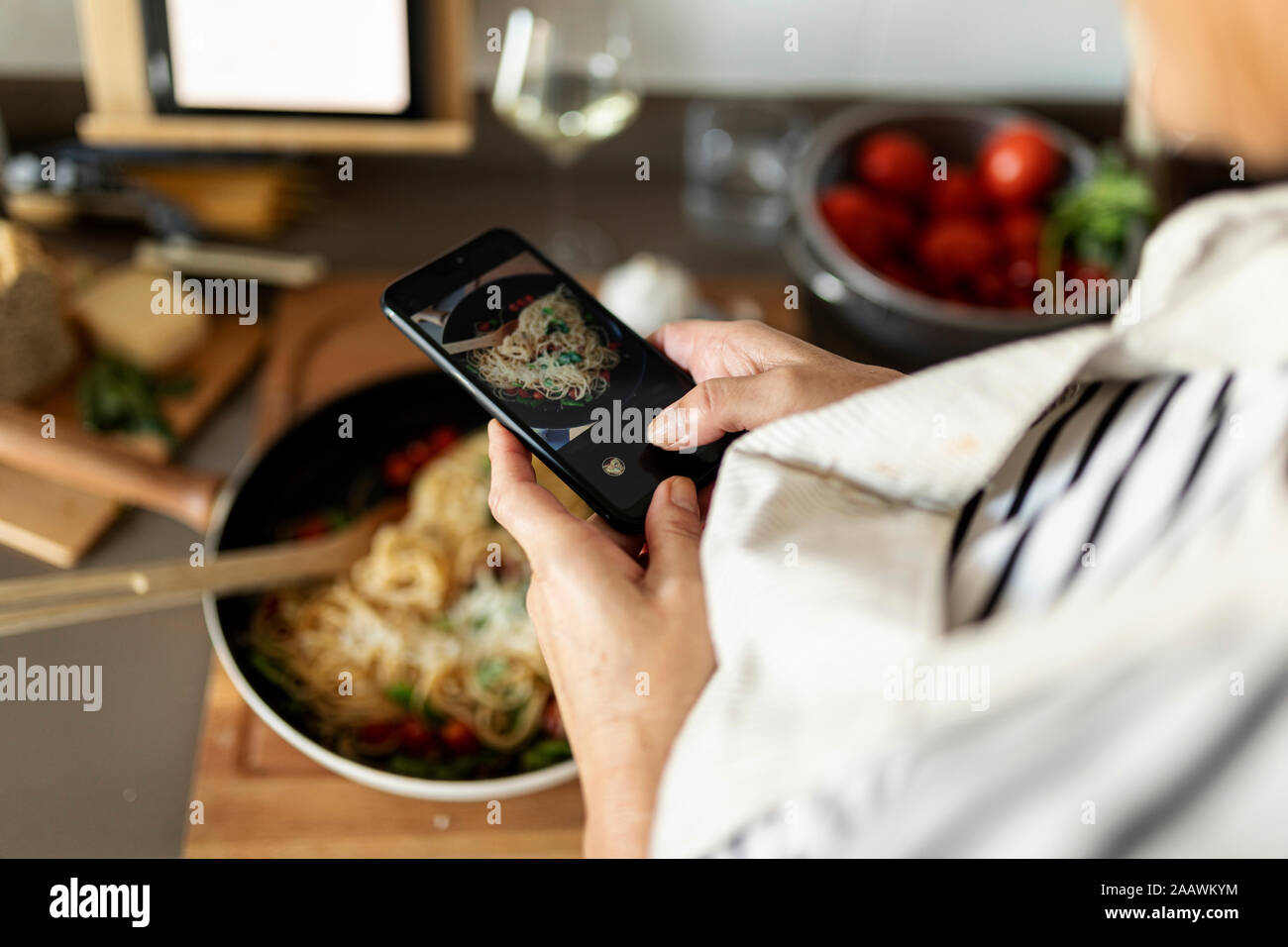 Close-up di donna prendendo immagini dello smartphone del suo piatto di pasta in cucina a casa Foto Stock