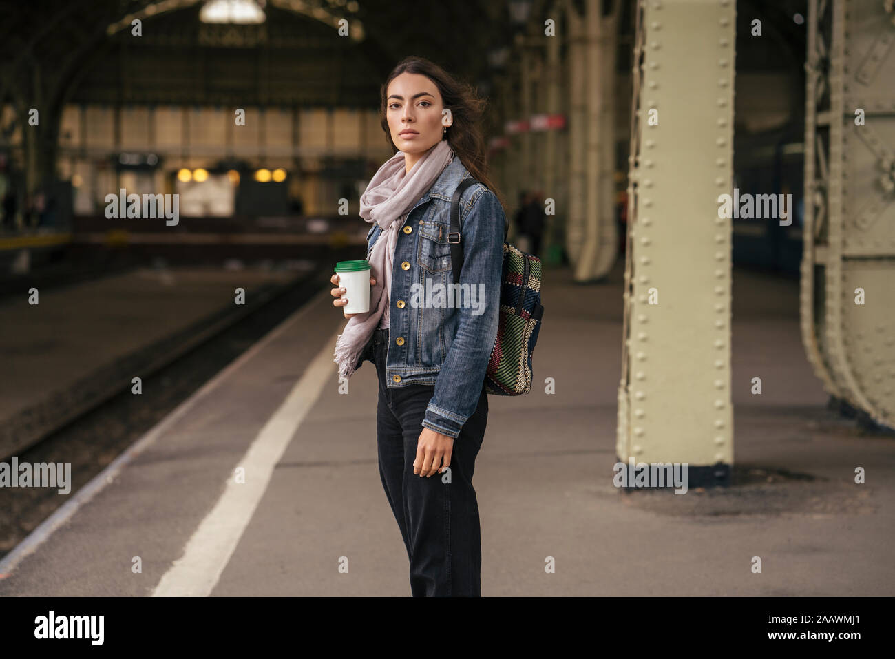 Giovani viaggiatori femmina con caffè per andare sulla piattaforma Foto Stock