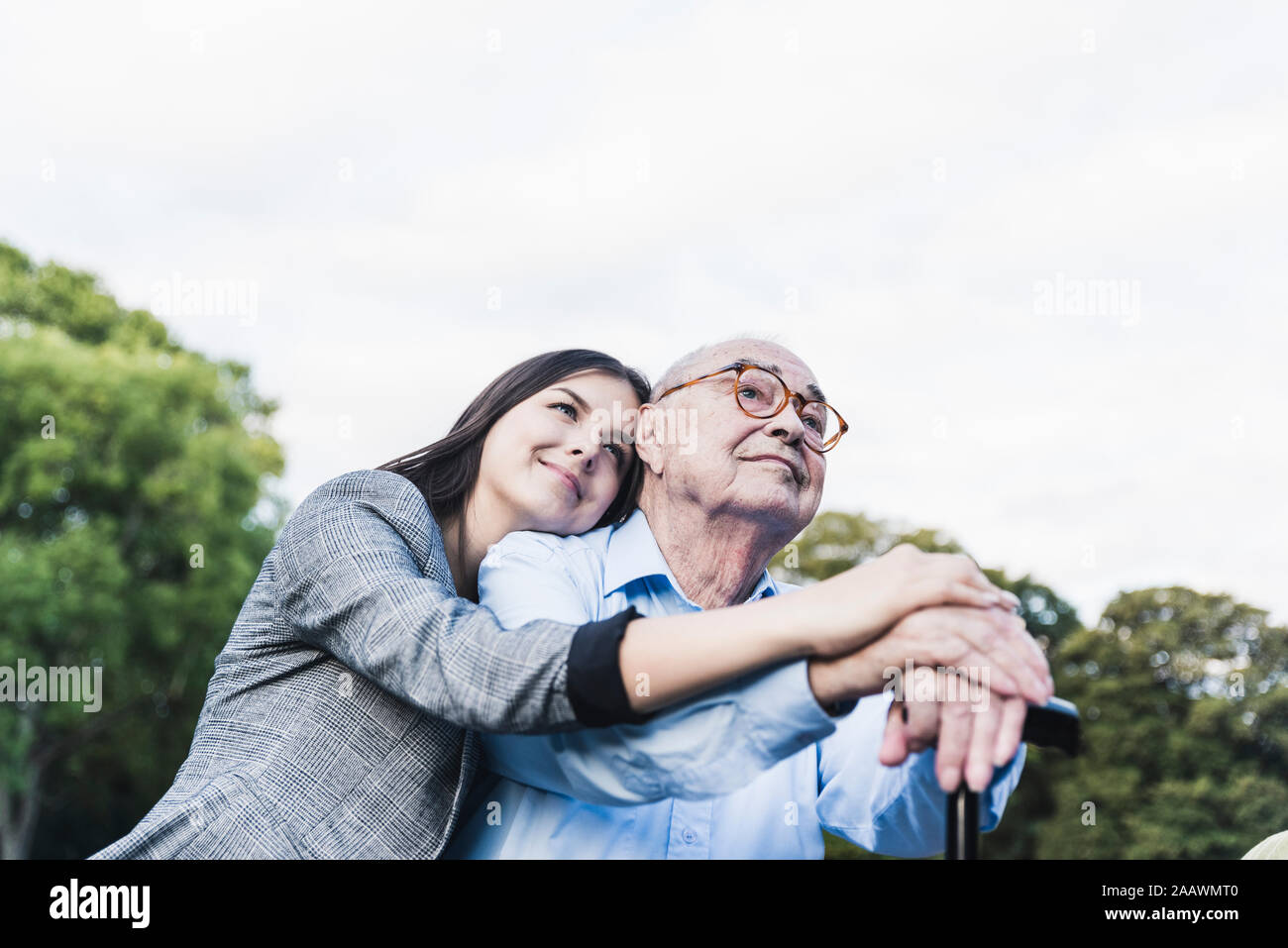 Ritratto di giovane donna che abbraccia il suo nonno in un parco Foto Stock