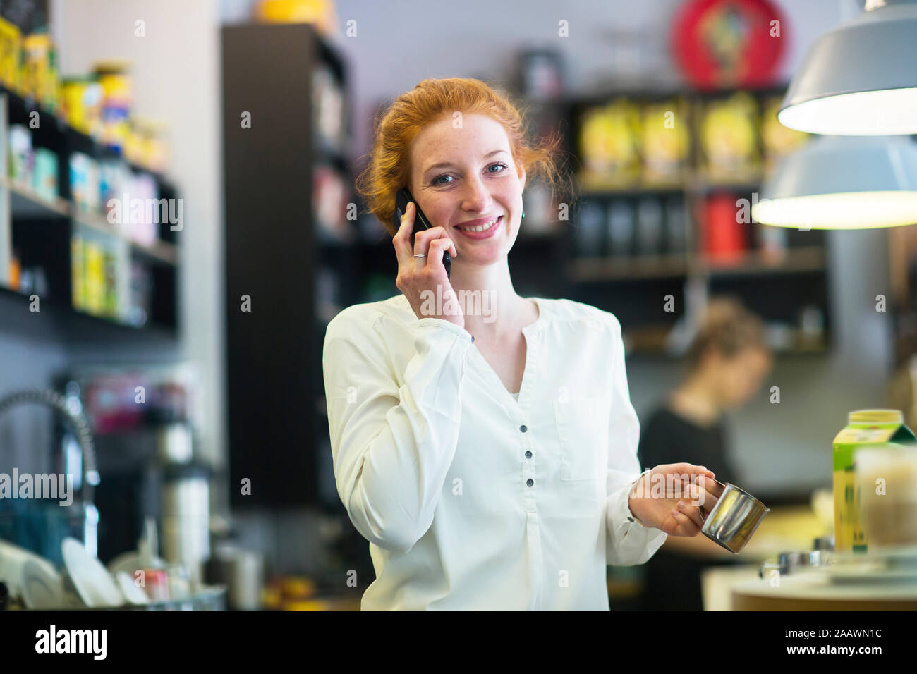 Giovane donna che lavorano nella caffetteria, usando il telefono Foto Stock