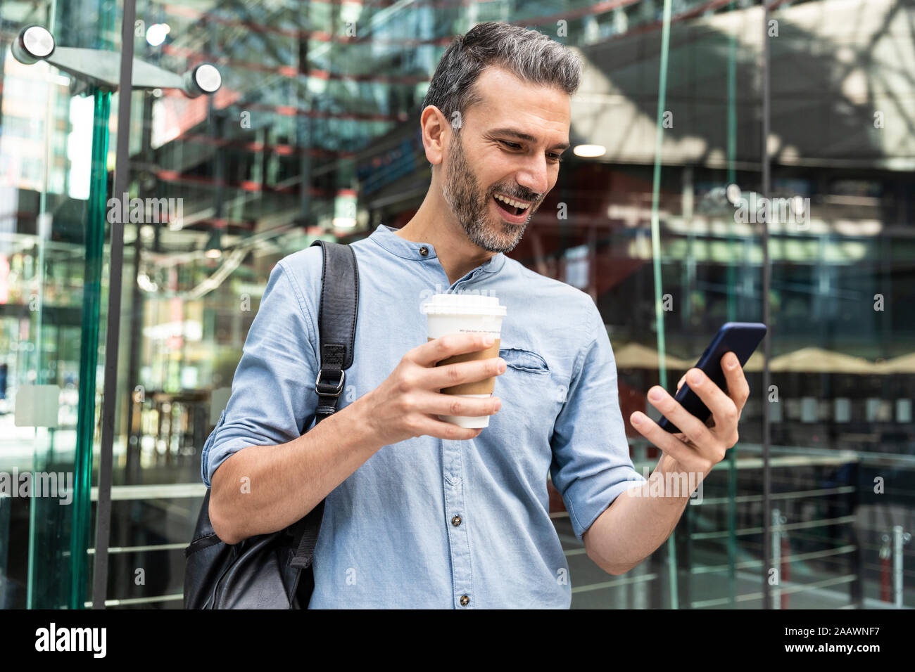 Happy businessman guardando lo smartphone nella città di Berlino, Germania Foto Stock