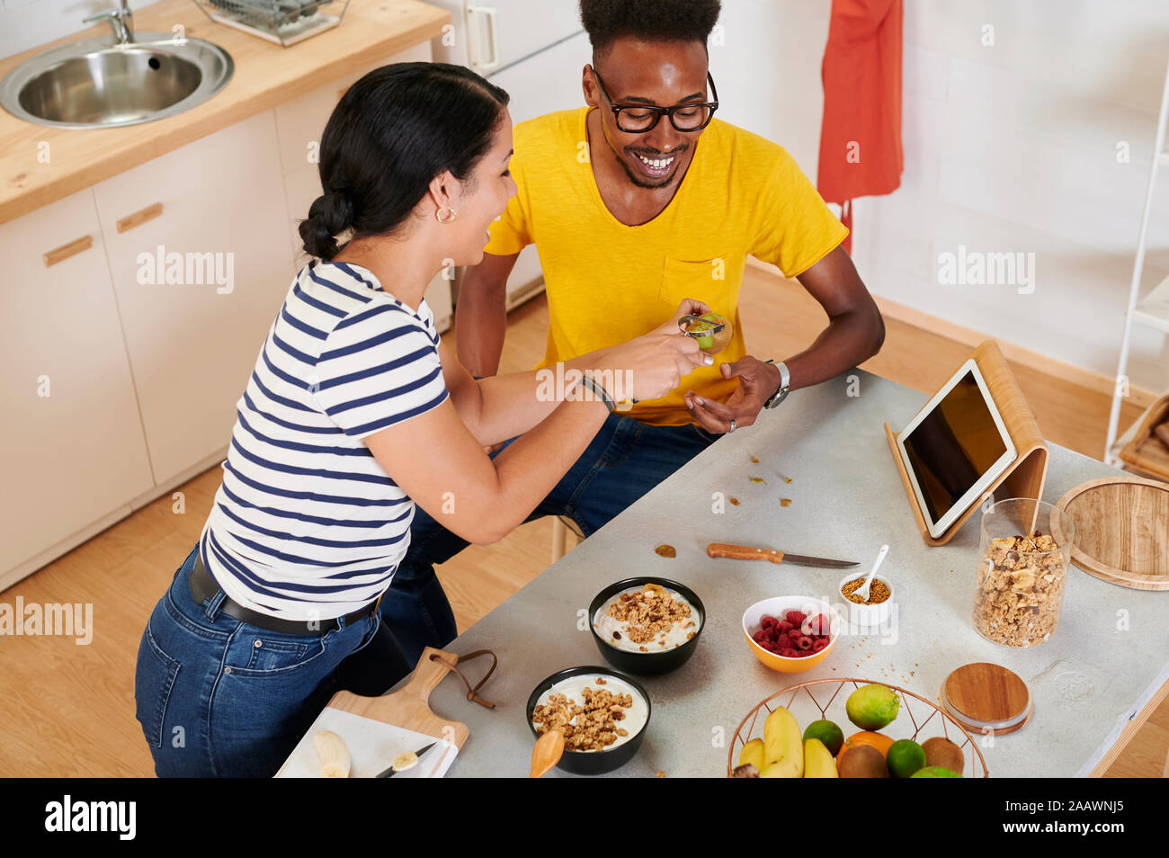 Coppia multietnica breakfasting insieme in cucina, talbet nel supporto Foto Stock