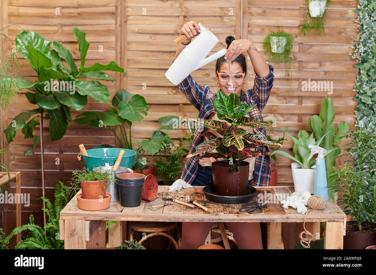 Ritratto di un sorridente giovane donna giardinaggio sul suo terrazzo Foto Stock
