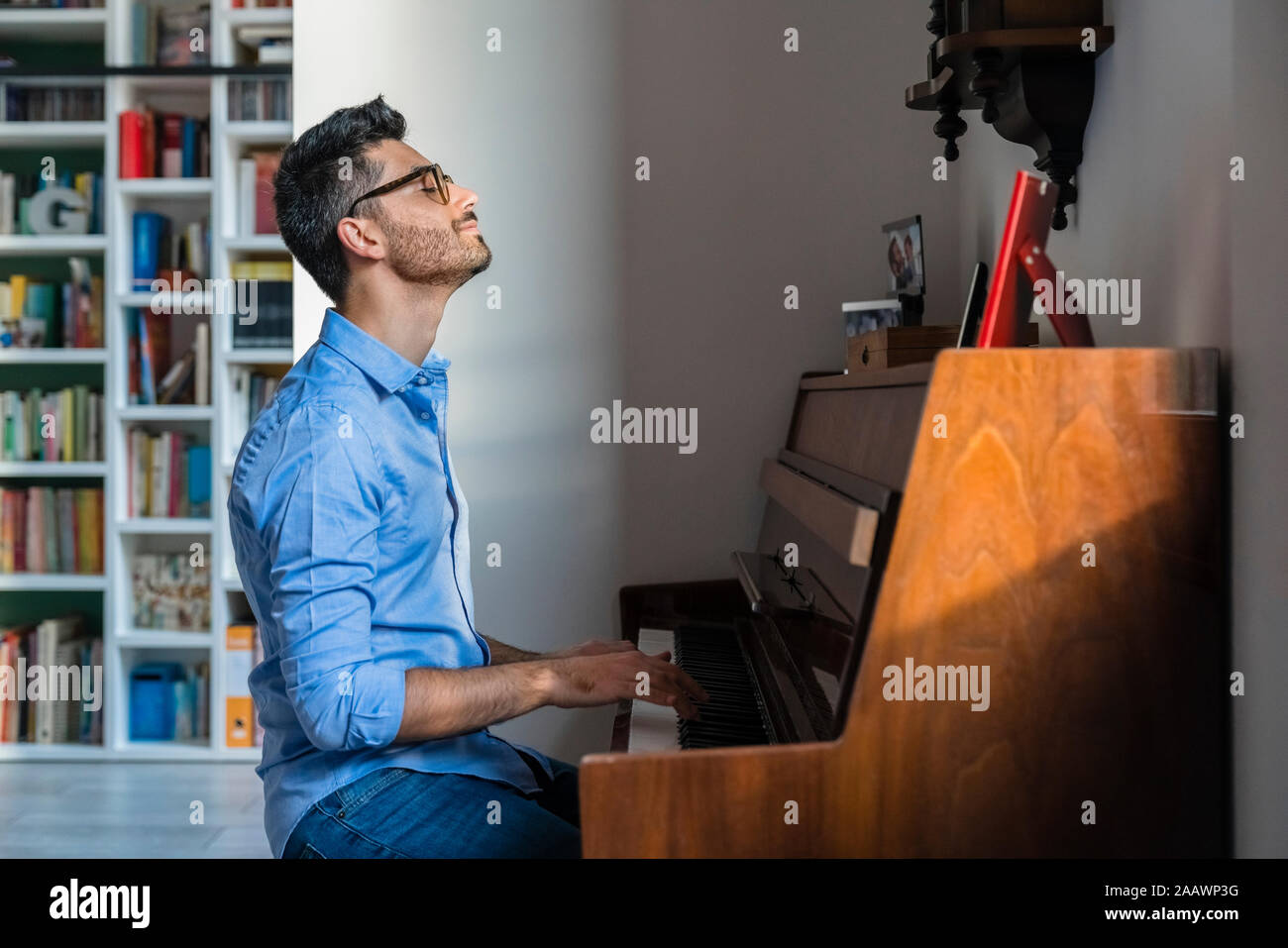 Sorridente giovane con gli occhi chiusi suonare il pianoforte a casa Foto Stock
