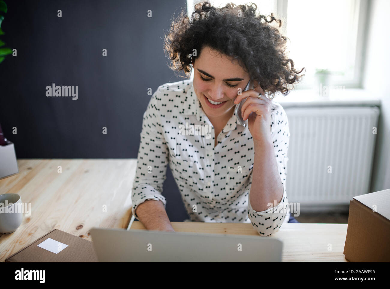 Sorridente giovane donna al telefono in ufficio in casa Foto Stock