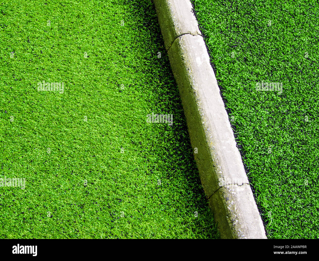 Texture plastica di erba artificiale e il confine di cemento del cortile della scuola Foto Stock