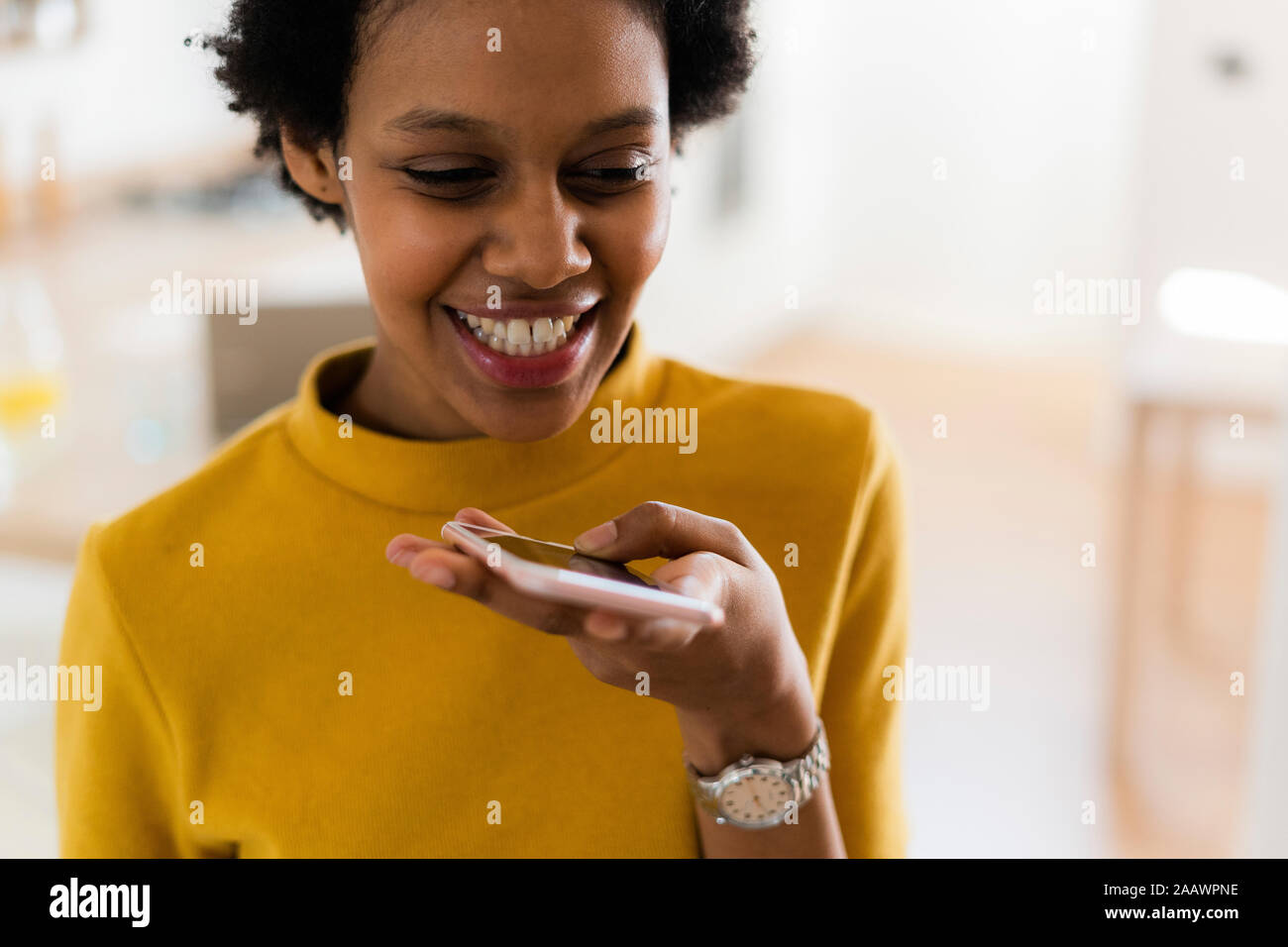 Felice giovane donna utilizza lo smartphone a casa Foto Stock