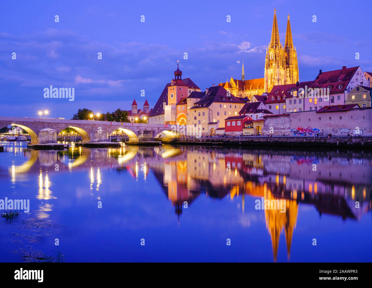Ponte di pietra sul fiume Danubio in città illuminata al crepuscolo, Regensburg, Alto Palatinato, Baviera, Germania Foto Stock