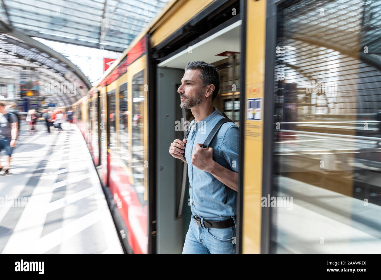 Uomo che sbarca dal treno alla piattaforma della stazione, Berlino, Germania Foto Stock