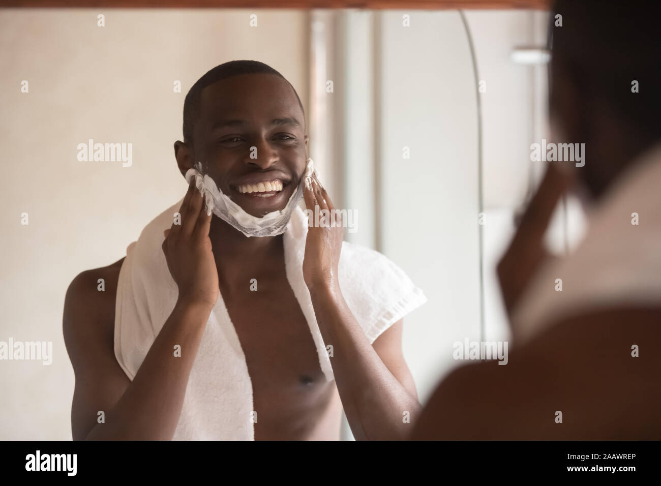 African American uomo guarda a specchio per rasatura in bagno Foto Stock