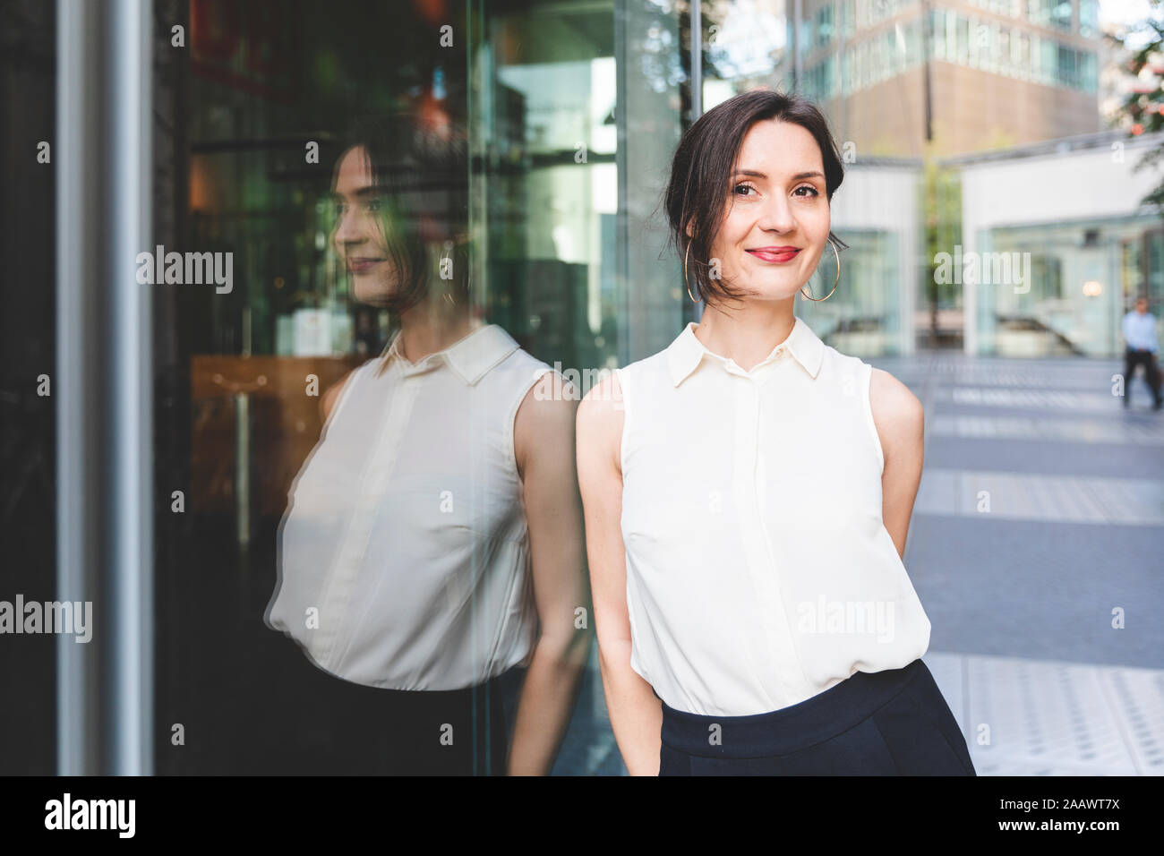 Ritratto di fiducioso giovane imprenditrice riflessa nella parte anteriore in vetro, Berlino, Germania Foto Stock