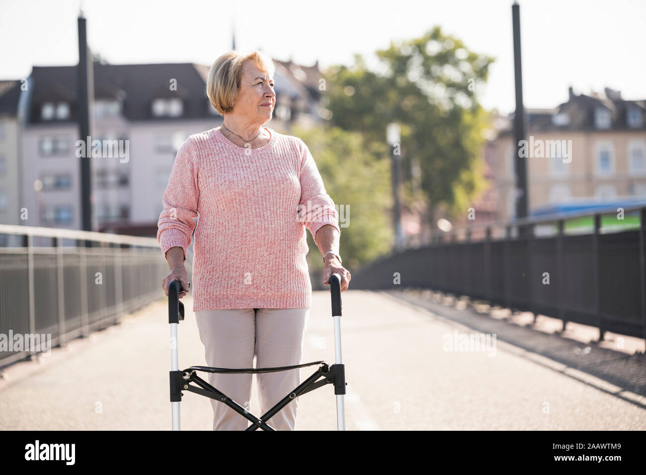 Senior donna con scuotipaglia con ruote su passerella Foto Stock