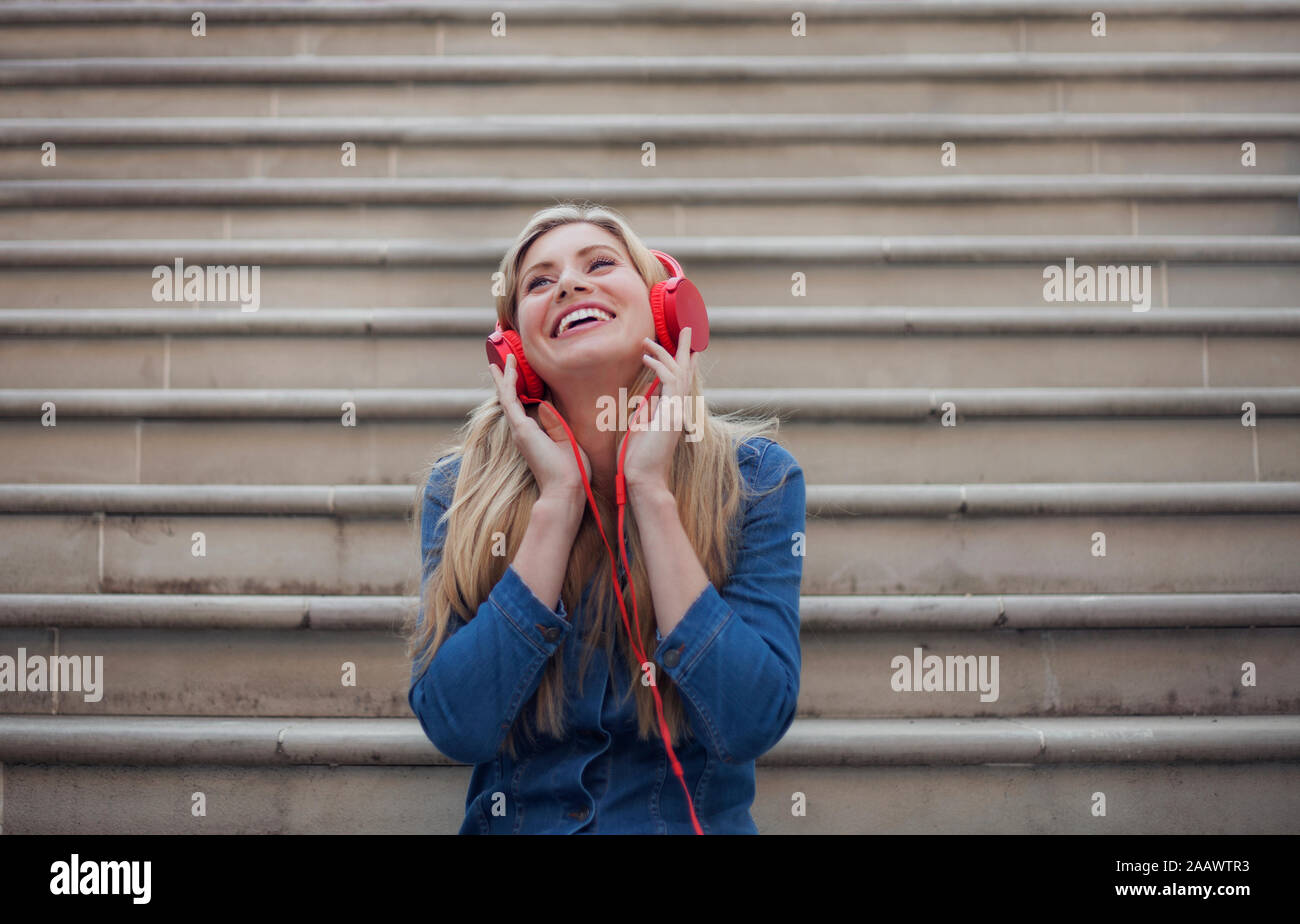 Ritratto di donna sorridente e ascoltare musica su Red Headphones Foto Stock