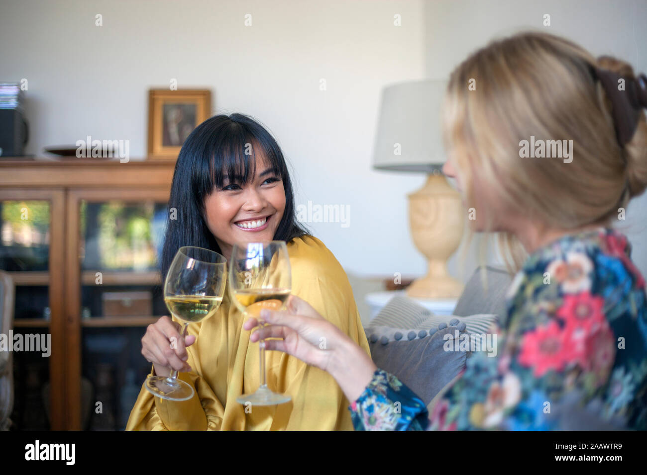 Due amici sittng sul lettino, bere vino, sorridente Foto Stock