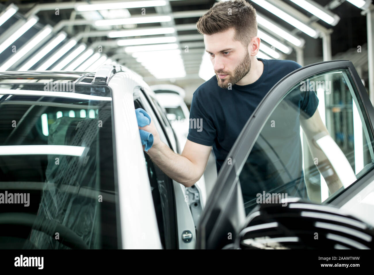 Uomo che lavora nella moderna fabbrica di automobili tergi vettura finita Foto Stock