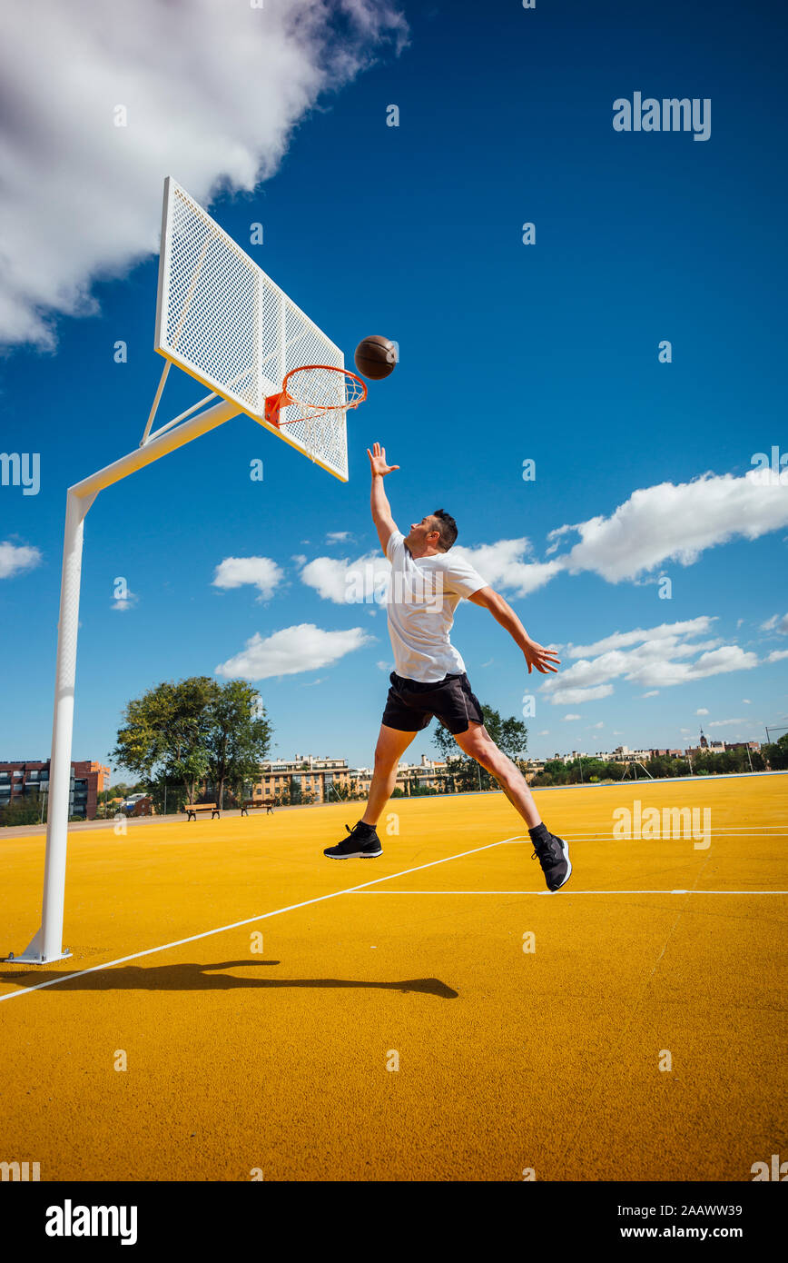 L'uomo giocare a basket sulla corte giallo, dunking Foto Stock