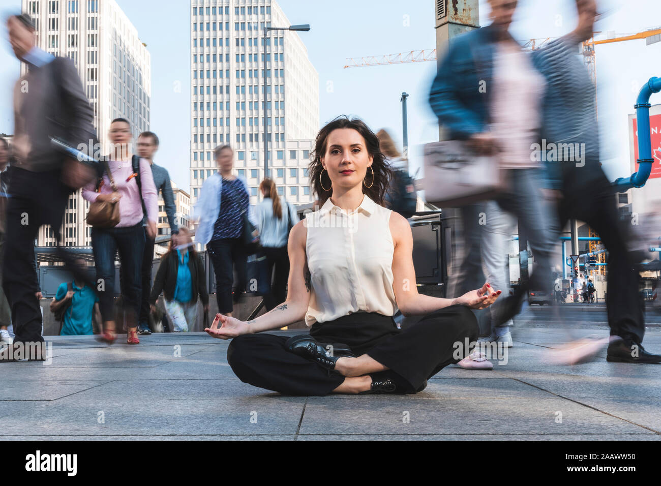 Giovane imprenditrice a praticare yoga nella città in ora di punta, Berlino, Germania Foto Stock