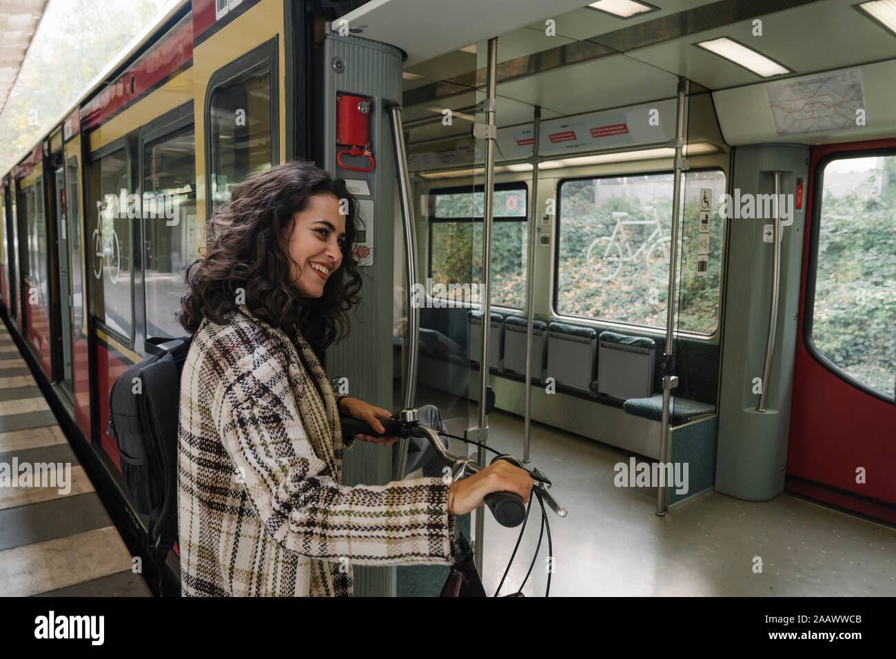 Donna sorridente con bicicletta entrando in un treno della metropolitana di Berlino, Germania Foto Stock