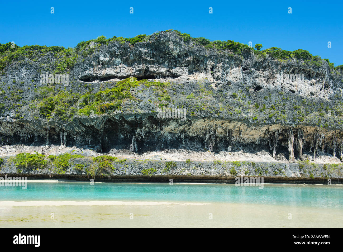 Spiaggia contro il grigio Lekiny scogliere, Ouvea, Isole della Lealtà, Nuova Caledonia Foto Stock