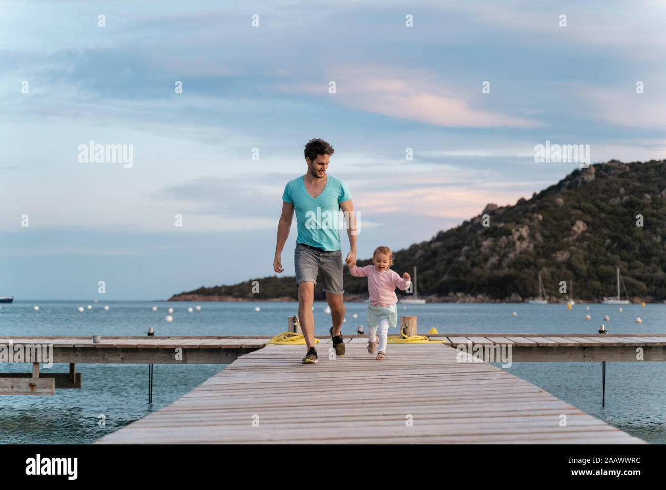 Padre Felice camminando con la figlia su un molo al tramonto Foto Stock