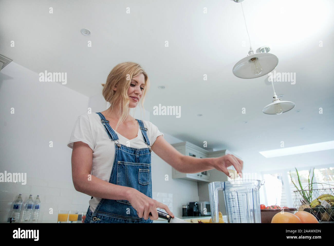 Donna preparazione frullato fresco nella sua cucina Foto Stock