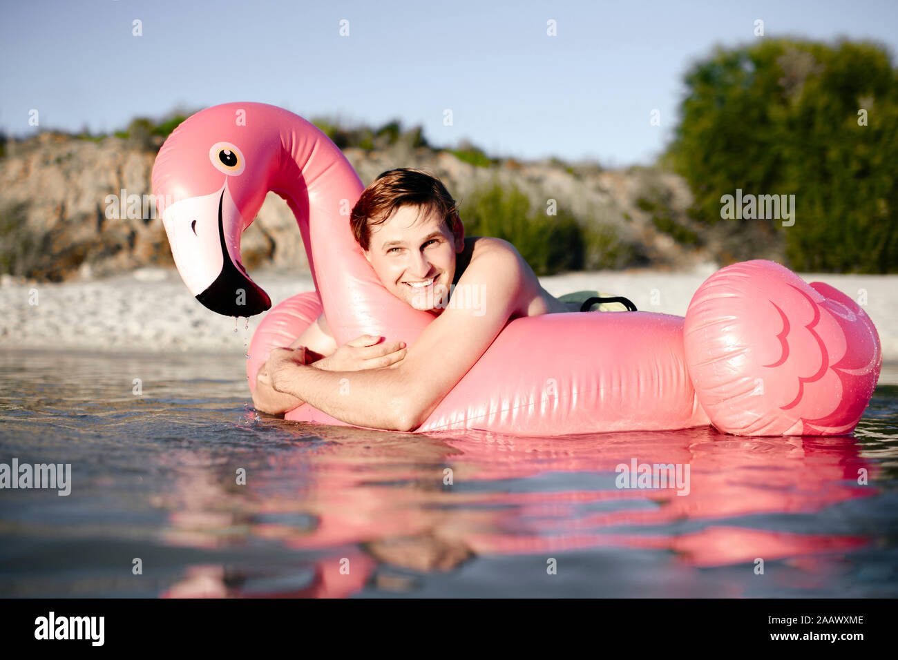 Giovane con flamingo piscina galleggiante sul lago Foto Stock
