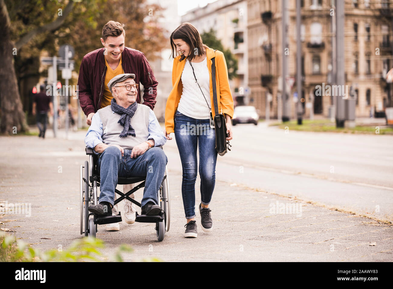 Felice l'uomo anziano in sedia a rotelle di trascorrere del tempo con i suoi nipoti Foto Stock