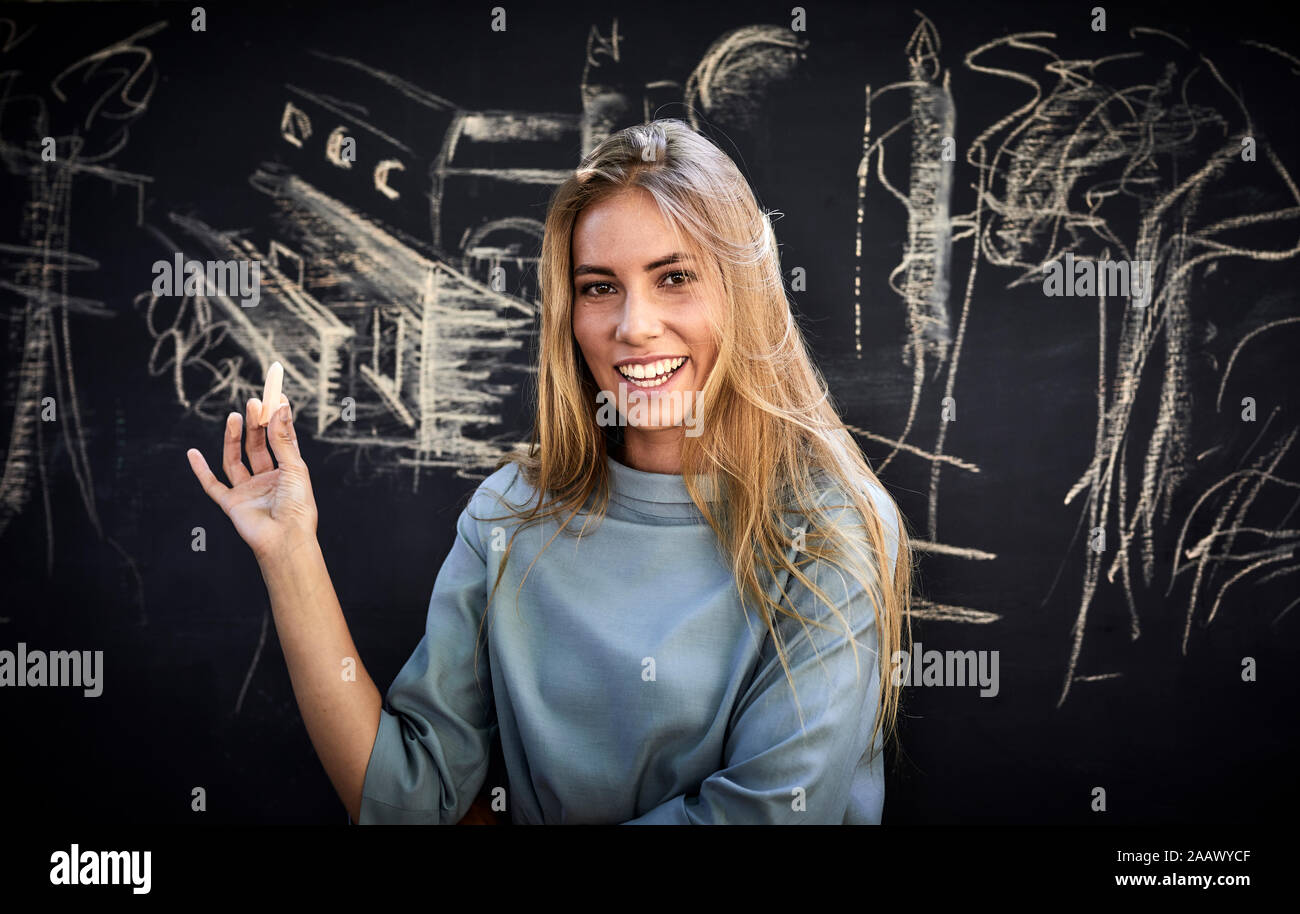Ritratto di un sorridente giovane donna di fronte a una lavagna Foto Stock