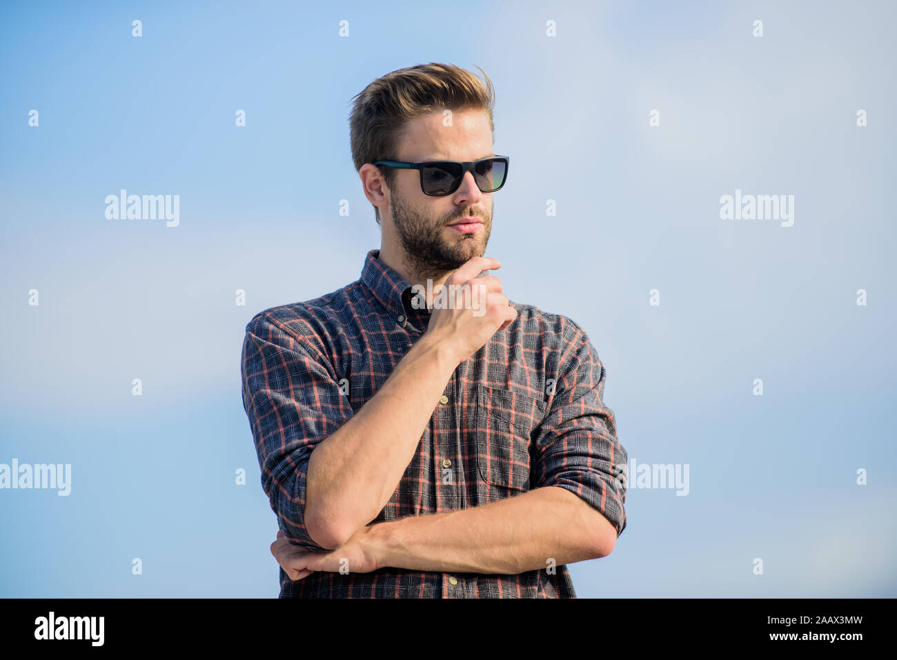 Protezione ultravioletta concetto. Visione perfetta. Vedere chiaro. Bel ragazzo di indossare occhiali da sole. Hipster uomo nel quartiere alla moda di occhiali da sole. Occhiali da sole alla moda. Uomo modello di occhiali all'aperto il cielo blu sullo sfondo. Foto Stock