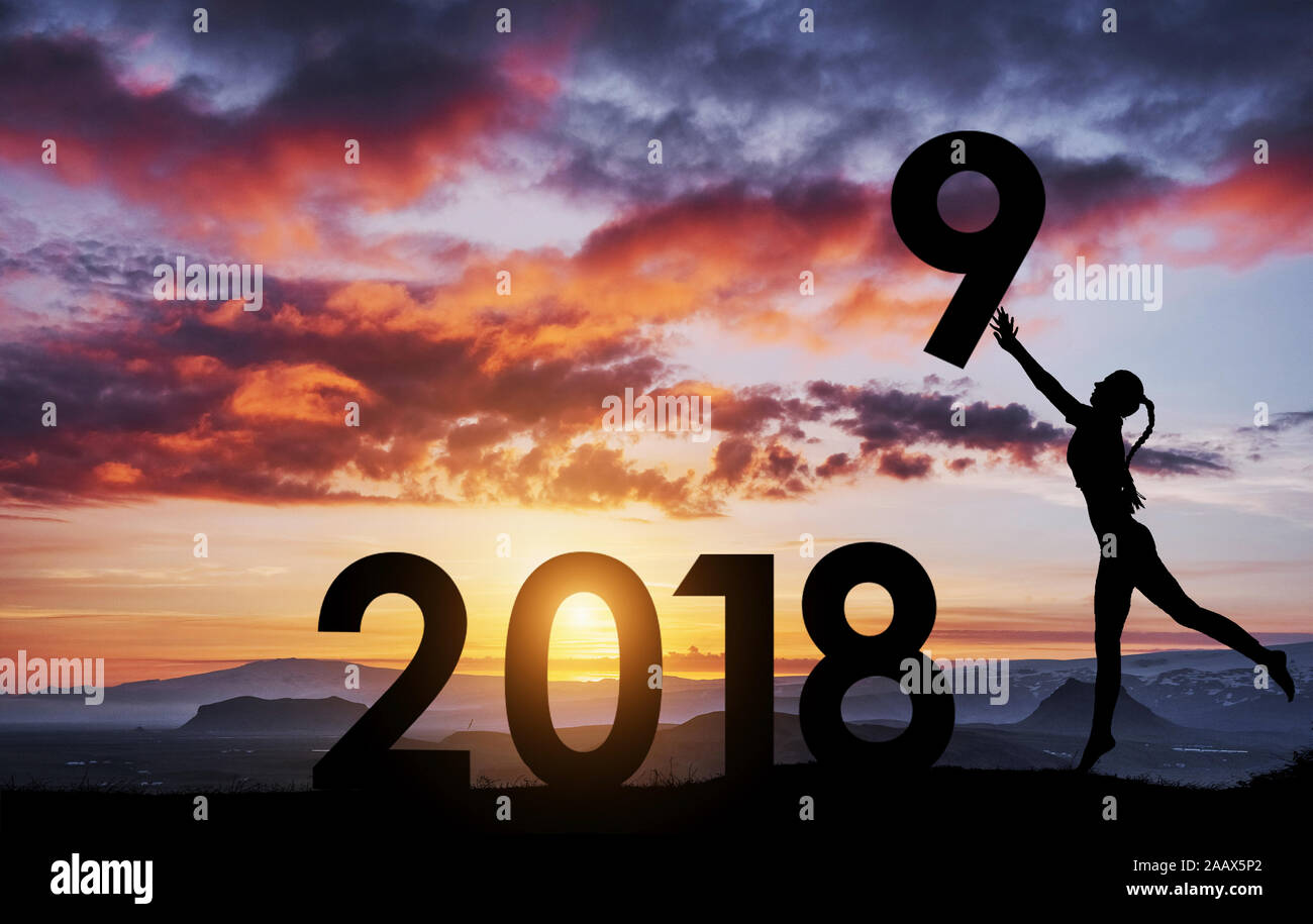 Silhouette della ragazza che contiene i numeri del nuovo anno al tramonto. Concetto di sostituzione 2018 a 2019 Foto Stock