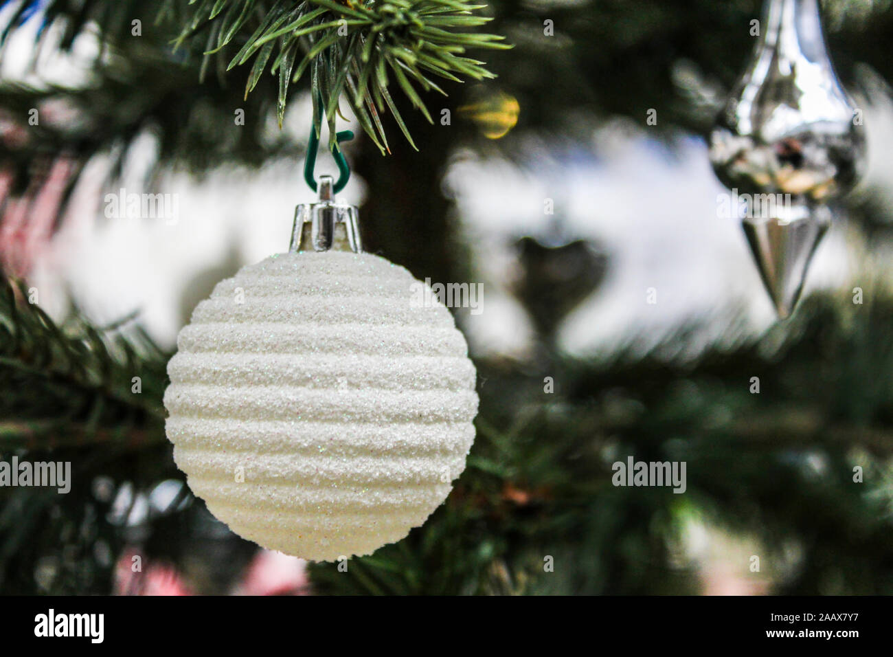 La sfera bianca su una verde albero di Natale di close-up Foto Stock