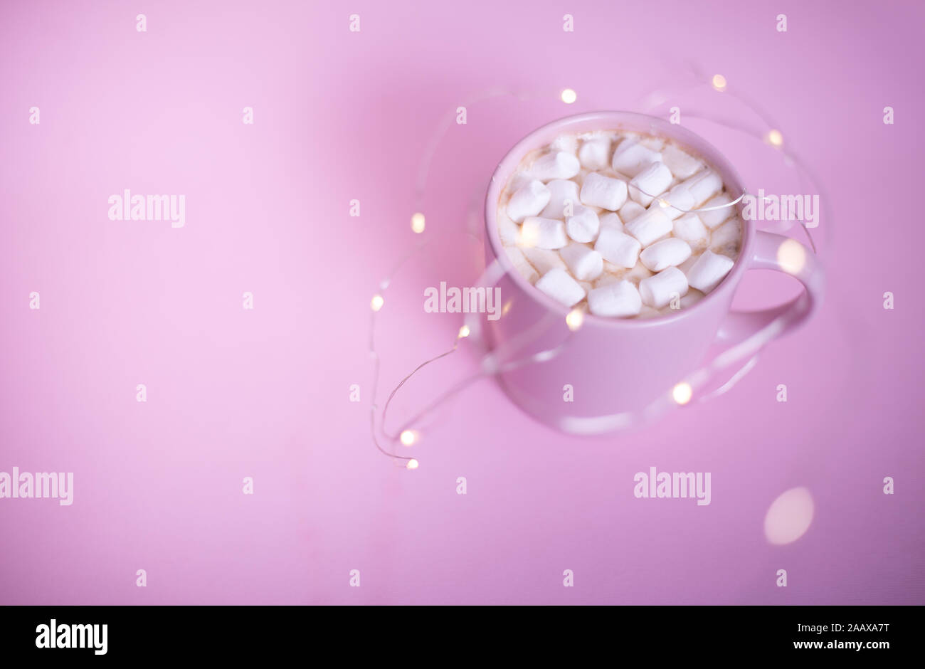 Rosa freddo tazza di cioccolata calda o di cacao caffè con marshmellows sul rosa luce backgroundwith bokeh di fondo e lo spazio per il testo Foto Stock