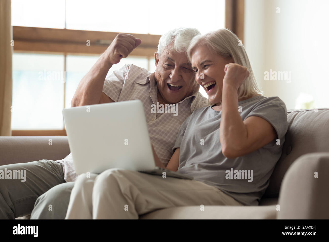 Euforico vecchio coniuge sposato celebrando lotteria online win. Foto Stock
