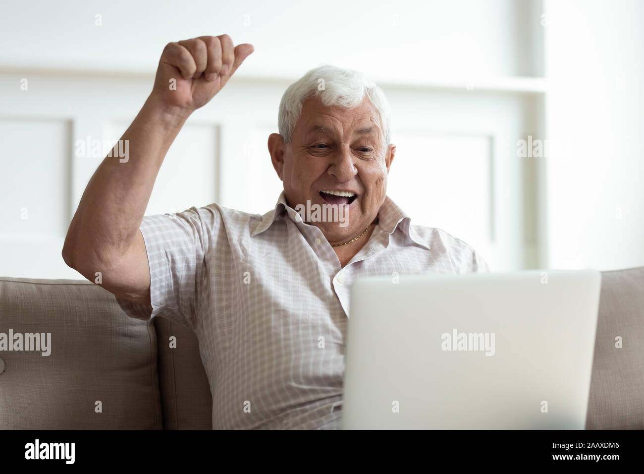 Euforico uomo vecchio guardando il monitor di un laptop, celebrando la vittoria della lotteria. Foto Stock