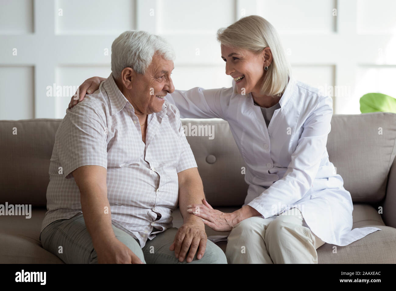 Cordiale coppia medico generale comunicante con piacevole 80s paziente. Foto Stock