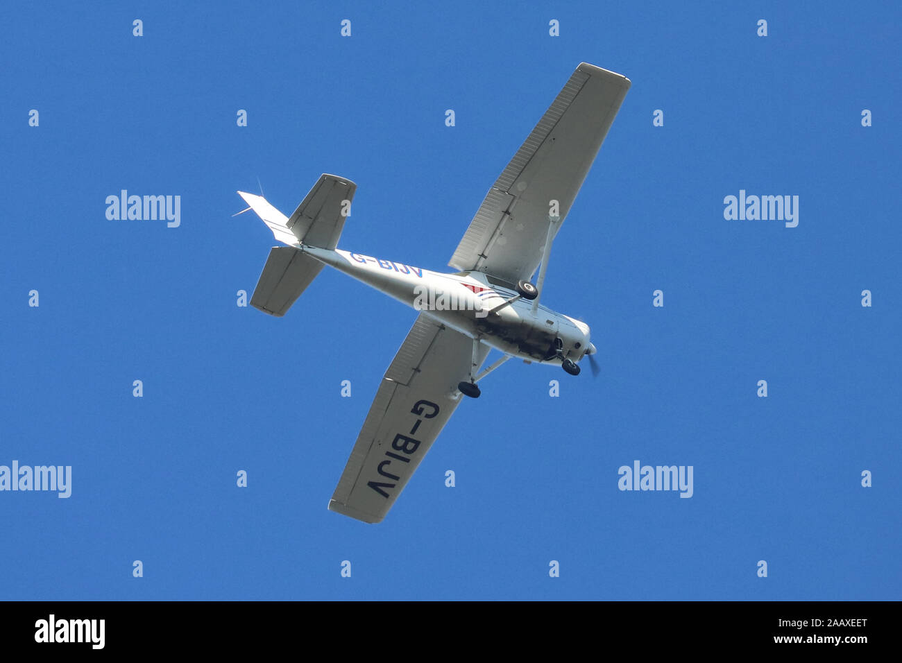 Reims-Cessna F152 un'unica luce di propulsori aerei G-BIJV flying overhead, impostare contro un cielo blu sullo sfondo. Foto Stock