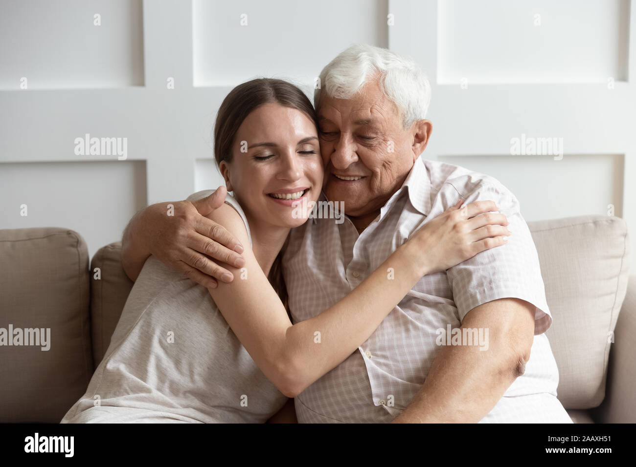 Caring adulto giovane donna cuddling felice vecchio annoso padre. Foto Stock