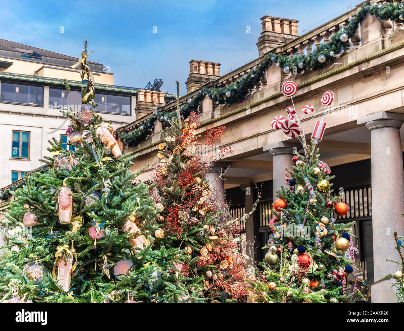 Alberi di Natale all'aperto nel mercato di Covent Garden Square decorata con ornamenti colorati e luci a Londra, Regno Unito Foto Stock