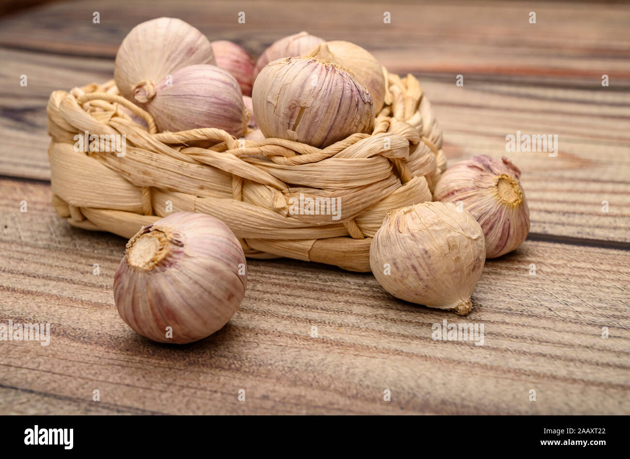 A pochi capi di giovani aglio in un cesto di vimini su un sfondo di legno. Raccolto autunnale. L'agricoltura moderna. Close up Foto Stock