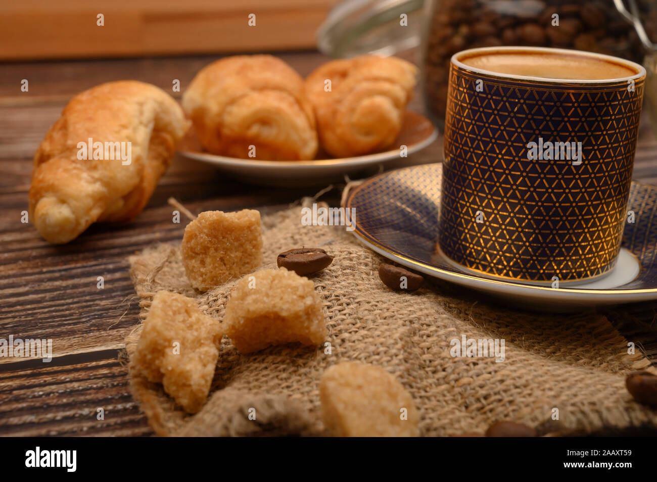 Una tazza di caffè e lo zucchero di canna, croissant su uno sfondo di legno. Close up Foto Stock