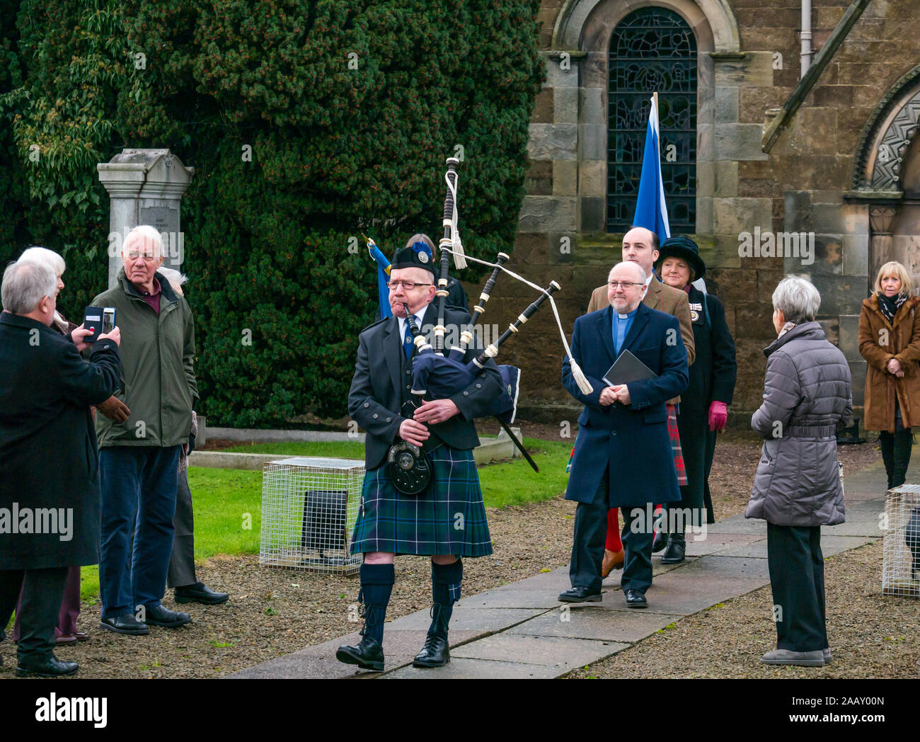 Athelstaneford, East Lothian, Scozia, Regno Unito. Il 24 novembre 2019. Si intraversa Festival: il primo giorno del festival annuale di mark St Andrew's Day avviene nel luogo di nascita della Scottish bandiera nazionale dove la si intraversa apparve nel cielo come un buon auspicio quando il Picts & scozzesi hanno sconfitto i sassoni guidati da Athelstan. Dopo un servizio di chiesa, Haddington Pipe Band piper conduce il ministro & Fraser Thompson della bandiera scozzese fiducia al memoriale di benedire un nuovo si intraversa Foto Stock
