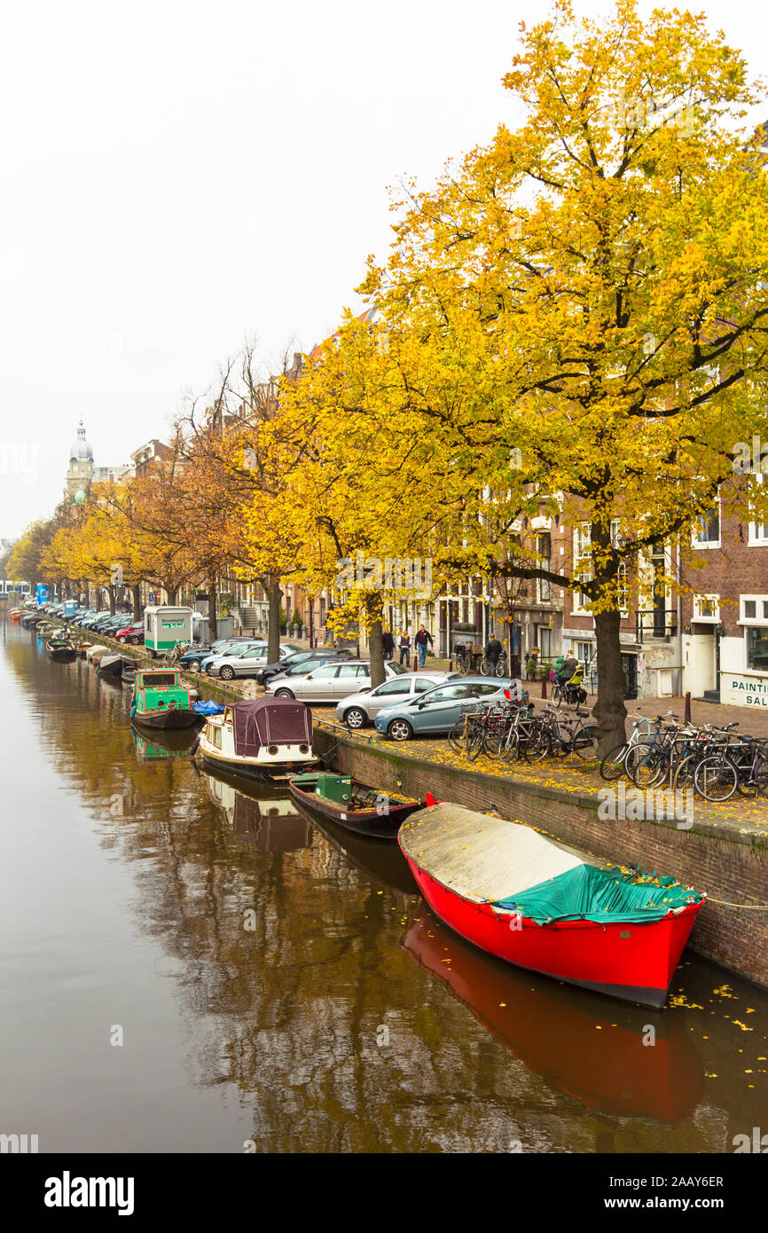 AMSTERDAM OLANDA PAESI BASSI CANAL in autunno con foglie d'oro sugli alberi e la piccola barca rossa sull'acqua Foto Stock