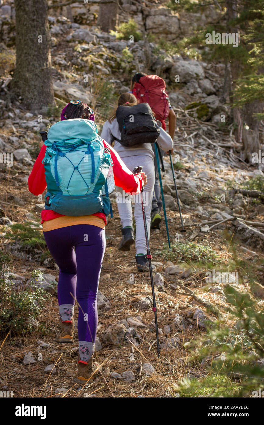 Arrampicata in montagna. Tre persone andare in salita con i pali trekking e zaini. Foto Stock