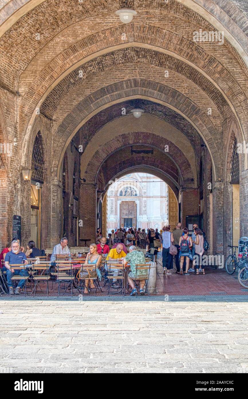 Bologna, Italia - 21 Luglio 2019: turisti e cittadini sotto il portico di Piazza Maggiore, con la facciata in marmo della chiesa di San Petronio in Foto Stock