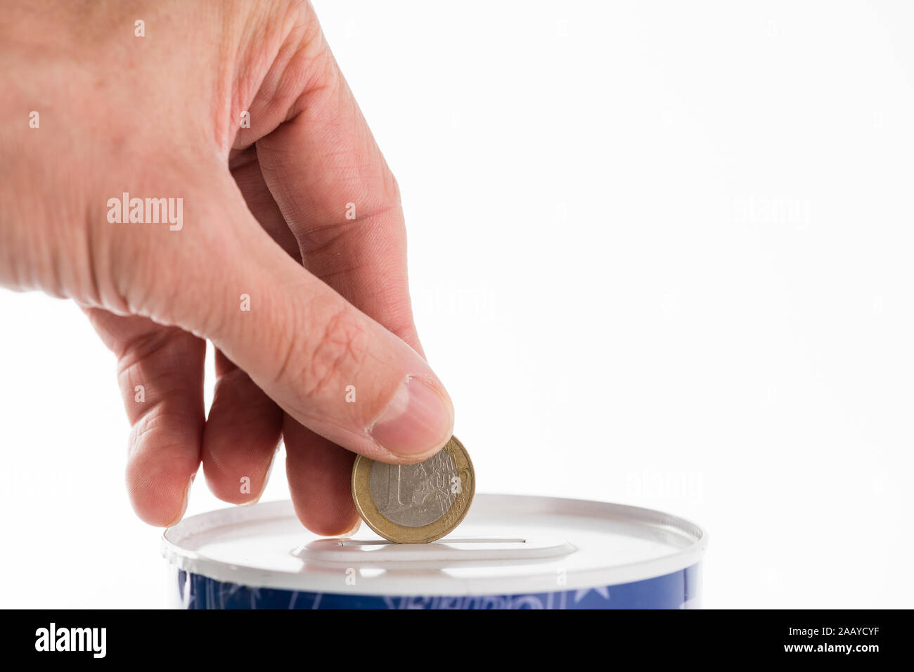 Maschio mettendo mano una moneta da un euro in barattolo di latta saving bank su sfondo bianco. Foto Stock
