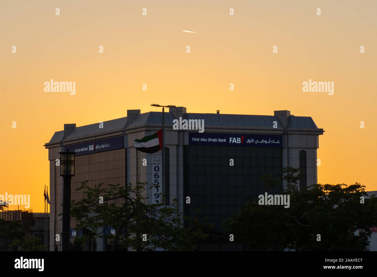 "Ras al Khaimah Ras al Khaimah/Emirati Arabi Uniti - 11/22/2019: " Prima di Abu Dhabi (FAB) Banca storefront blu durante un giallo dorato del tramonto. ' Foto Stock