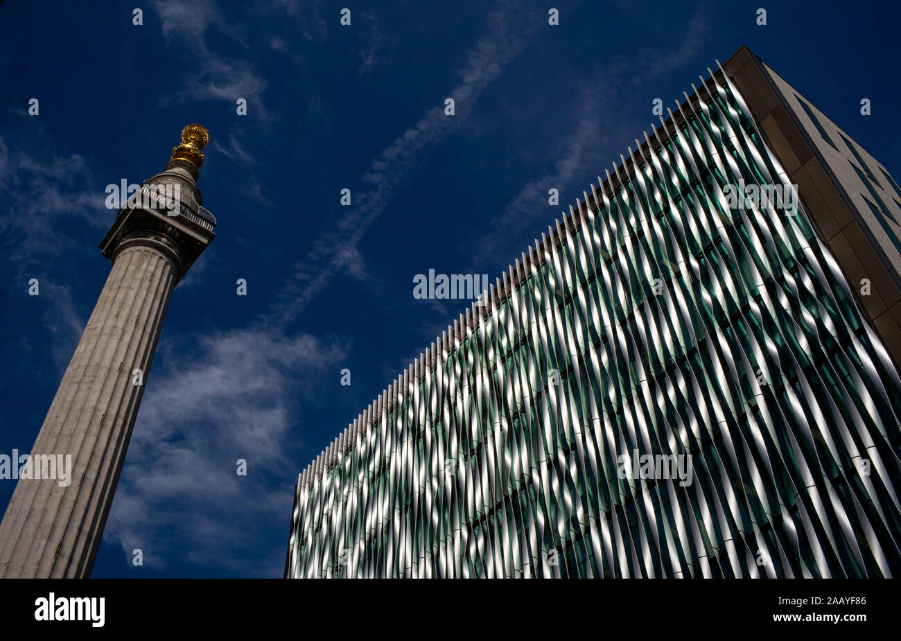 Monumento del Grande Incendio di Londra in pudding lane.Con una bassa prospettiva cercando con cielo blu, spazio copia e il contrasto tra architettura moderna Foto Stock