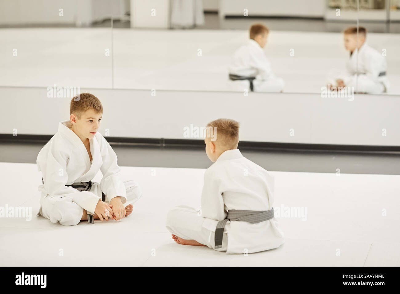 Due ragazzi in kimono bianco seduto sul pavimento di fronte a ogni altro essi discutendo sulla loro futura concorrenza Foto Stock